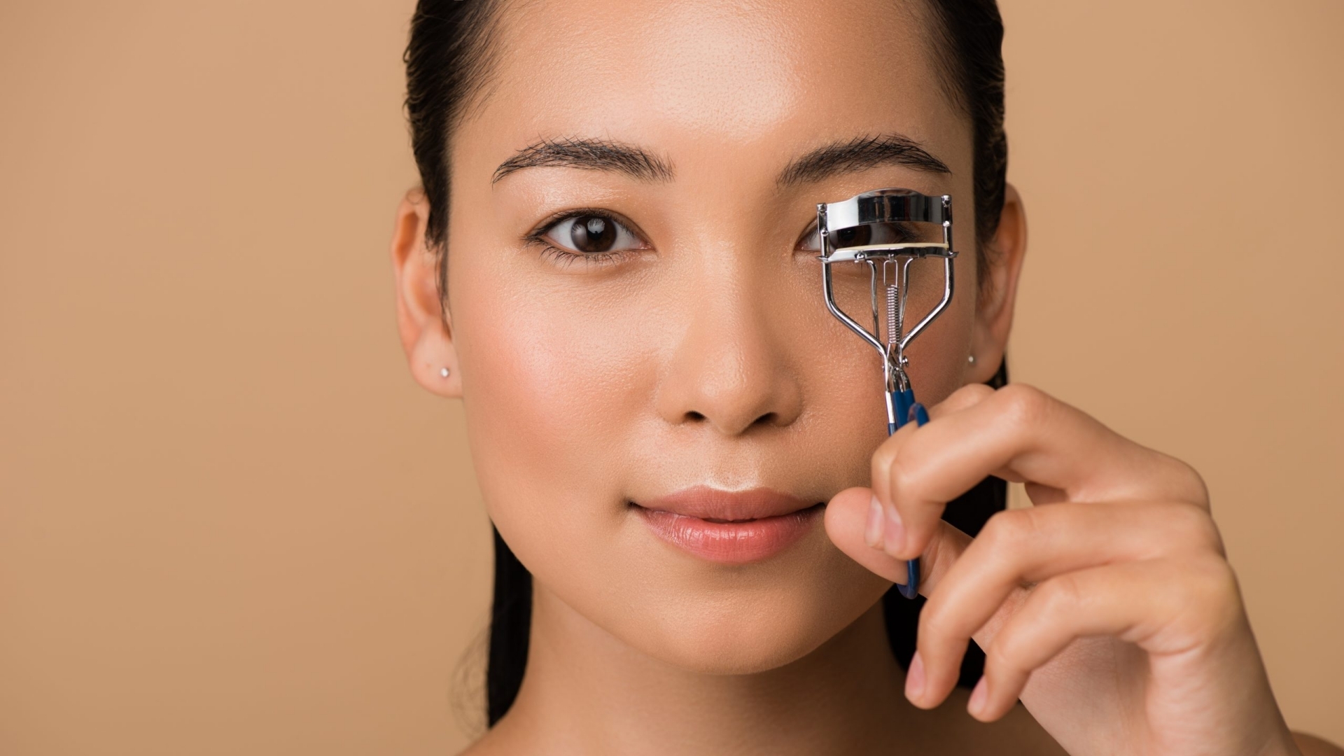 an asian woman who is using eyelash curler