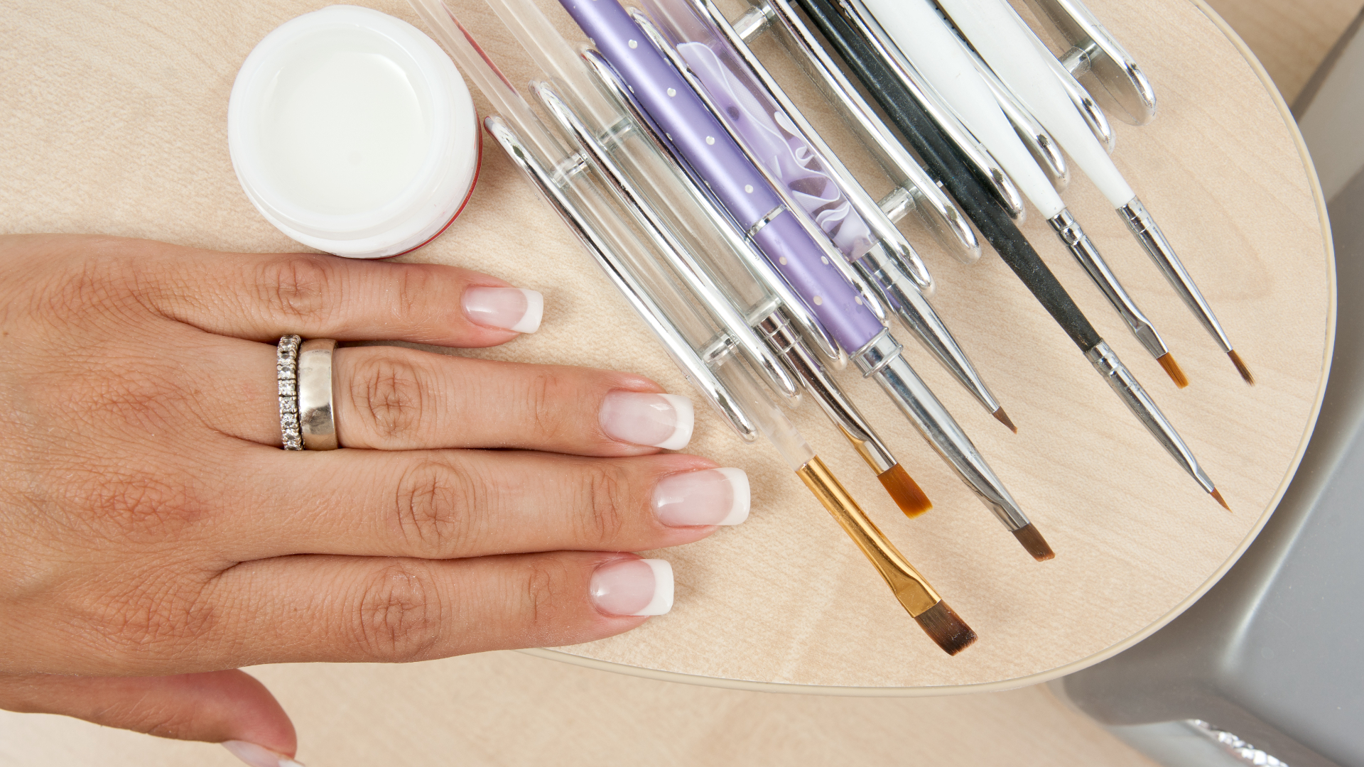 woman's hand beside the acrylic nail brushes