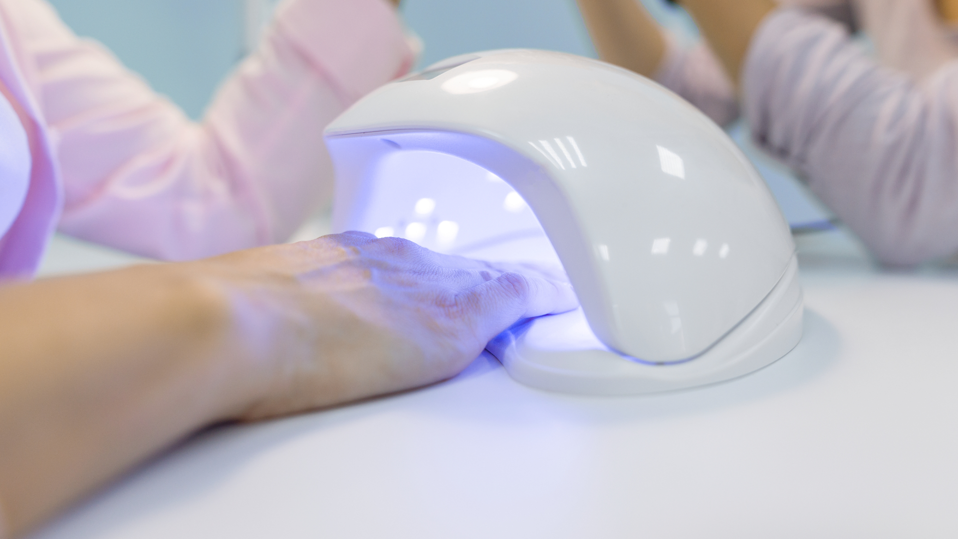 manicurist using UV light for fixing gel nail polish