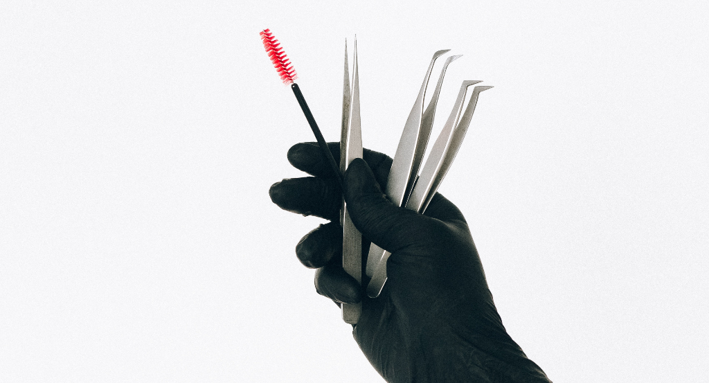 person wearing black gloves while holding brush and tweezers