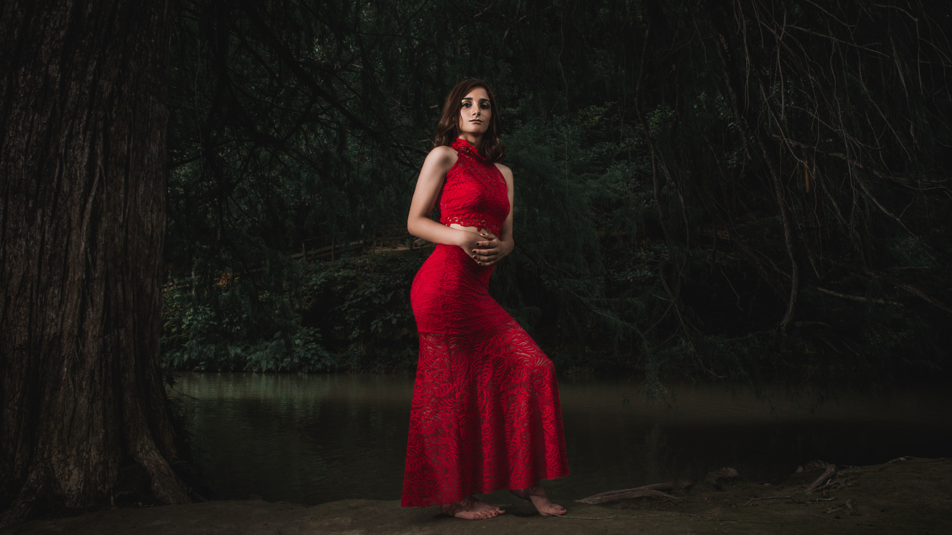 woman in red dress standing under a tree